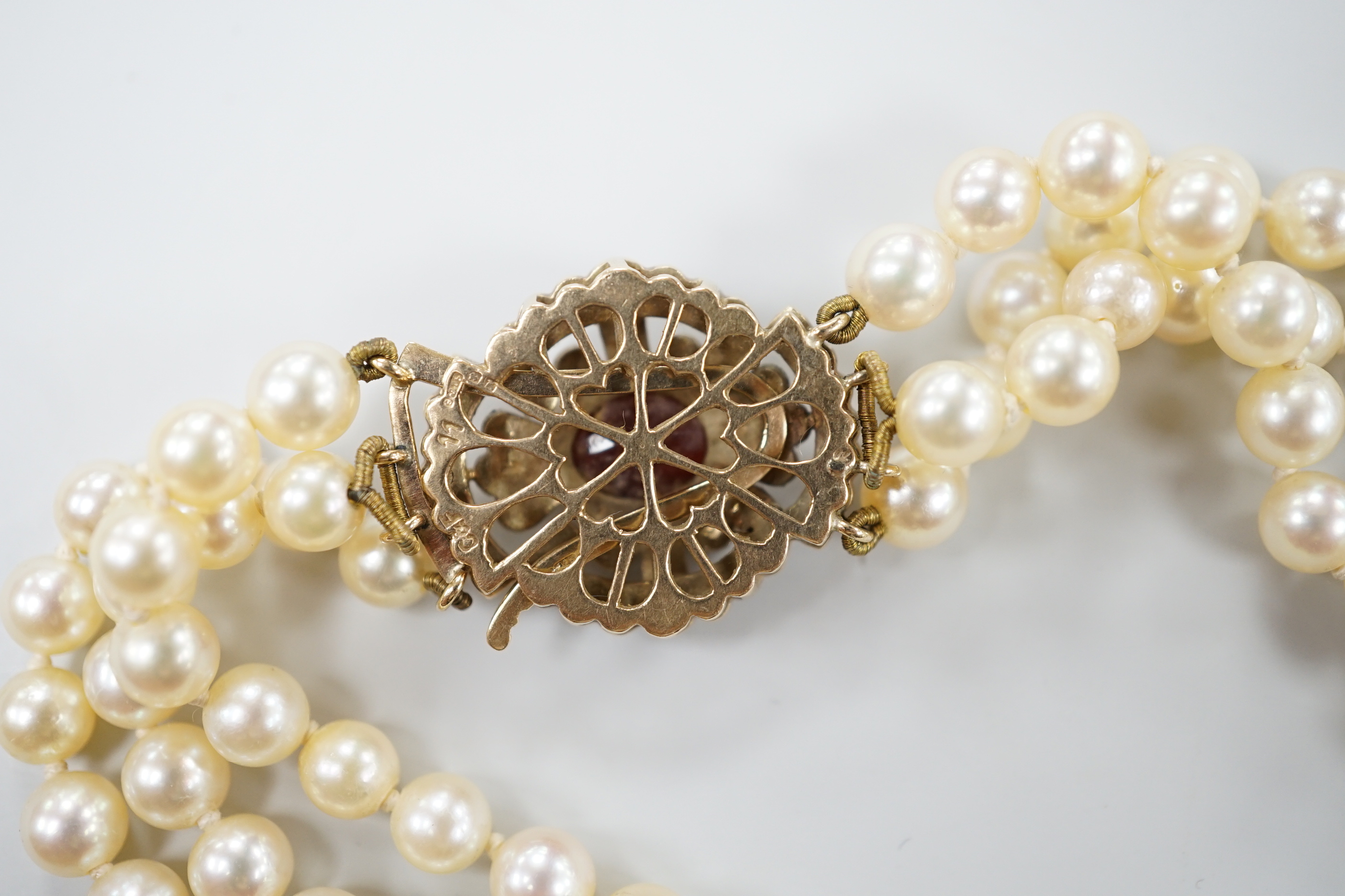 A 1960's triple strand cultured pearl choker necklace by Cropp & Farr, with 9ct gold, garnet and seed pearl set clasp, 39cm.